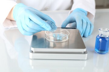Scientist weighing sample on scales at white mirror table, closeup