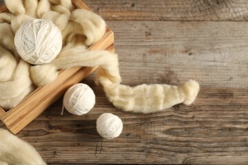 Felting wool and knitting yarn on wooden table, closeup. Space for text