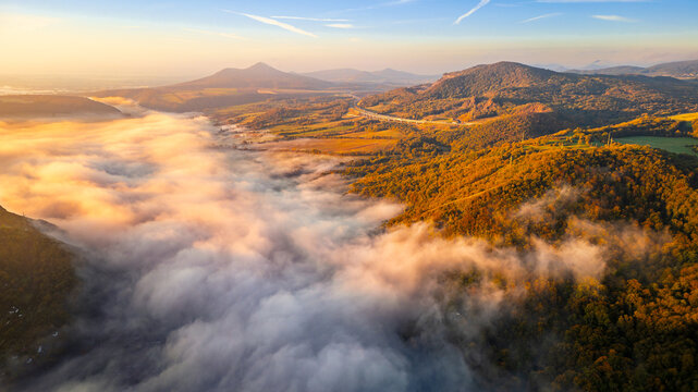 view from a drone at sunrise on the Czech Central Highlands surrounded by morning fog over the Elbe River.