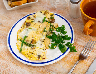 Delicious scrambled eggs with vegetables, chicken and mushrooms served for breakfast