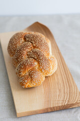 sesame seed crusted challah bread on wooden board with curved edge