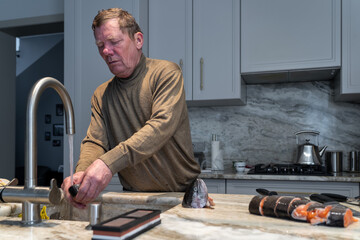 Preparing fish at home: Man washing fish at kitchen sink after filleting, showcasing kitchen...
