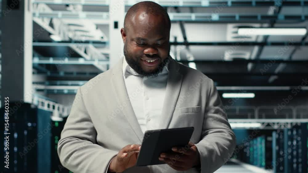 Poster close up of technician walking in data center, using tablet to check equipment for system stability.