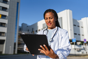Portrait of african american woman doctor examining clipboard