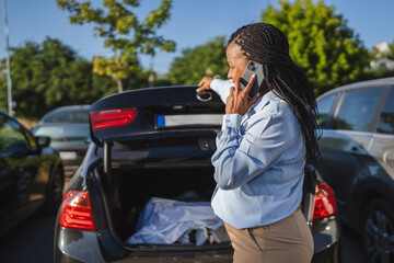 african american businesswoman talk on cellphone while close car trunk