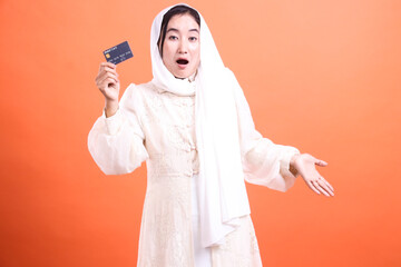 Surprised Muslim Woman Holding Credit Card: A Shocking Discovery, showcasing unexpected financial...