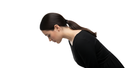 A woman with dark hair in a ponytail wearing a black shirt looking down against a black background space on transparent background