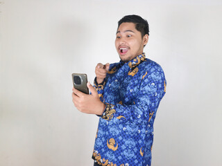 Indonesian civil servant male looks at and points at the mobile phone he is holding with a shocked...