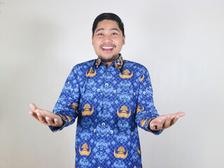 Indonesian civil servant man standing with happy and friendly expression, showing welcome gesture....