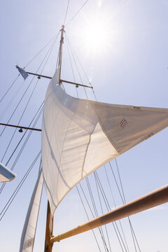 Low angle looking up at a yacht's sail into a bright sunny sky