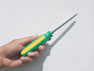 Hand holding green and yellow screwdriver