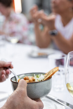 Woman taking a bit of appetizer at a group dinner with white wine. 