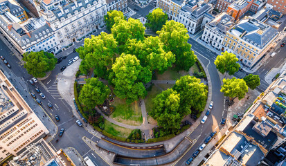Aerial view of Cavendish Square Gardens in London surrounded by classic architecture, roads, and vehicles on a bright summer day.