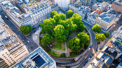 Aerial view of Cavendish Square Gardens in London surrounded by classic architecture, roads, and vehicles on a bright summer day.
