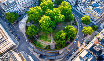 Aerial view of Cavendish Square Gardens in London surrounded by classic architecture, roads, and vehicles on a bright summer day.