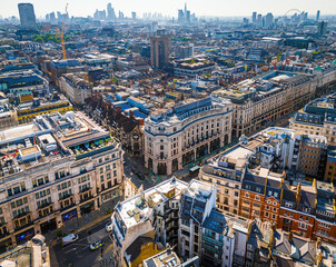 Aerial view of Regent Street in London with its sweeping curve, elegant architecture, red buses, and busy city streets on a clear day.