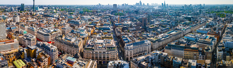 Aerial view of Regent Street in London with its sweeping curve, elegant architecture, red buses, and busy city streets on a clear day.