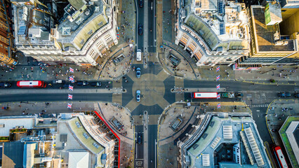 Aerial view of Oxford Circus in London with busy streets, iconic architecture, and red double-decker buses on a clear, sunny day