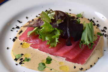 Closeup plate with tuna carpaccio garnished with mixed lettuce greens