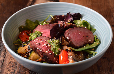 Bowl with warm sliced roast beef and grilled vegetables salad
