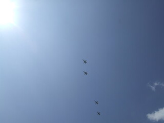 Four aircraft flying in a clear blue sky, with bright sunlight illuminating the scene, showcasing aviation in action and the beauty of flight dynamics