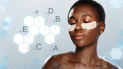 Woman enjoying a skincare treatment with under-eye patches, relaxed in studio with blue backdrop