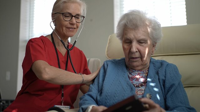 A caregiver warmly attends to an elderly woman, providing support and companionship in a healthcare facility. Their interaction promotes comfort and well-being.