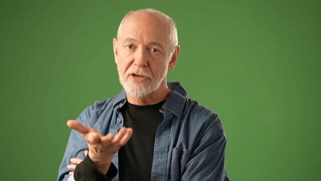 POV of mature man with a beard gestures expressively while standing against a solid green screen backdrop, showcasing a range of emotions and engagement.