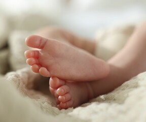 Cute newborn baby lying on bed indoors, closeup