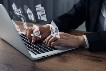 Real estate agent looking for housing via laptop at wooden table, closeup. Illustrations of...