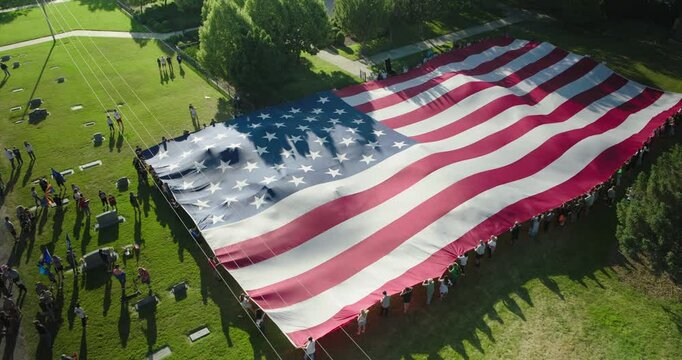 Flying over and away from beautiful American flag being held in grassy field