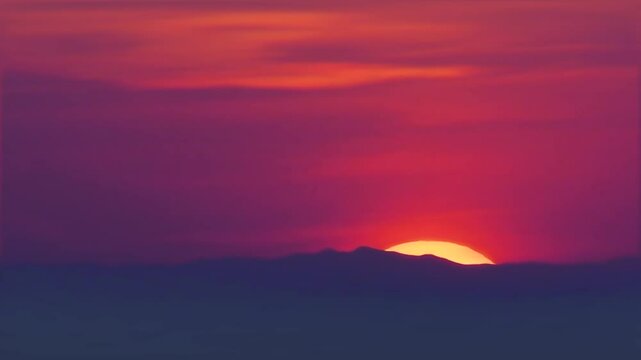 The last crescent of the sun disappears behind the ridges of California's Temblor Range beneath a red-orange marbled sky.