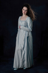 A Regency woman wearing a cotton dress with her long hair blowing in the wind against a studio...