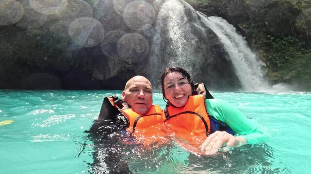 Happy couple floating close to waterfall in Kawasan canyoneering route Excited couple enjoying Kawasan waterfall adventure in Cebu, Philippines