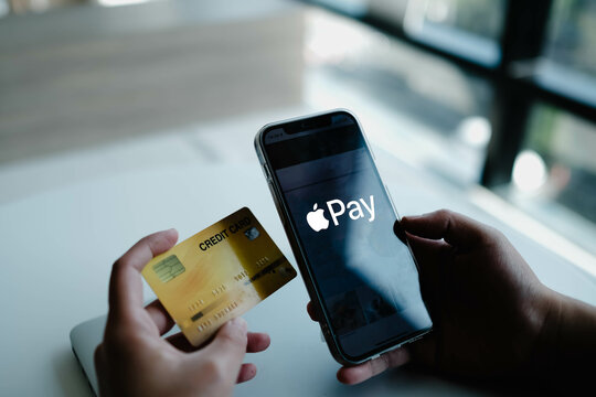 Bangkok, Thailand. June 25, 2025; A person holding a credit card and a smartphone displaying the Apple Pay logo, representing mobile and contactless payment technology.