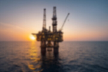Obraz premium Blurry photo of gas mine construction in the middle of the sea, sunset.