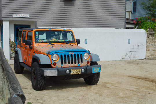 Brightly Painted Jeep Wrangler Parked on Sandy Ground Near Urban Building  Editorial Use Only, June 6, 2025, St. Augustine, Florida, USA. Orange and blue Jeep with unique decorations is parked on a sa