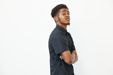 Confident young black man with arms crossed, showcasing a modern black shirt against a minimalist...