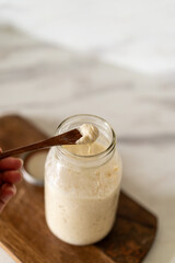 Freshly prepared sourdough bread dough rests on parchment near a container of active starter and a mixing bowl, showcasing the art of home baking.