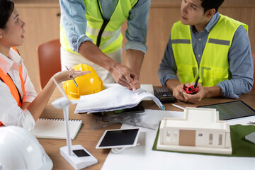 Sustainable Architecture Discussion. Team collaborating on eco-friendly building plans with models.