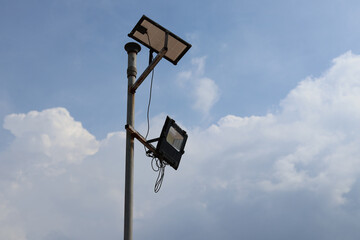 Tall street light pole with solar panels and LED floodlights installed against partly cloudy sky...