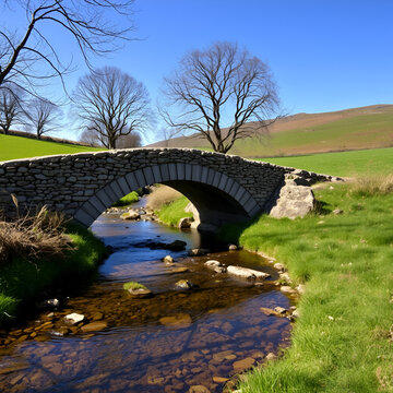 A small stone bridge crossing over a babbling brook in a countryside scene.