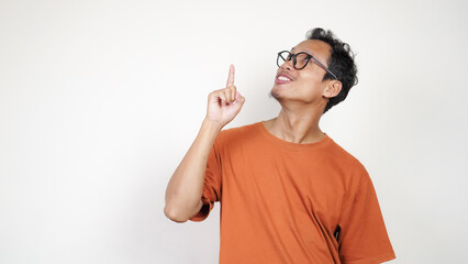 A man in an orange shirt is smiling and pointing to the camera