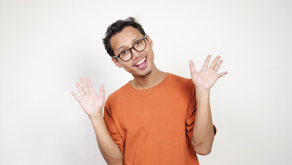 A man in an orange shirt is smiling and pointing to the camera