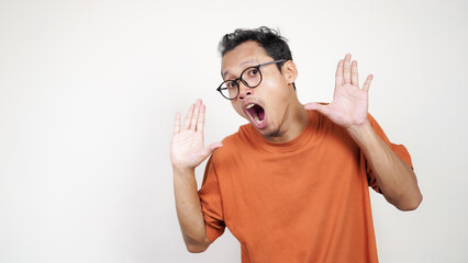A man in an orange shirt is smiling and pointing to the camera