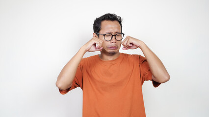 A man in an orange shirt is wearing glasses and is making a face