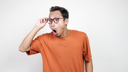 A man wearing glasses and an orange shirt is looking surprised
