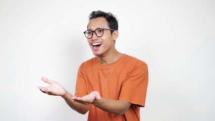 A man in an orange shirt is smiling and pointing to the camera
