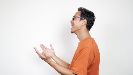 A man in an orange shirt is smiling and pointing to the camera
