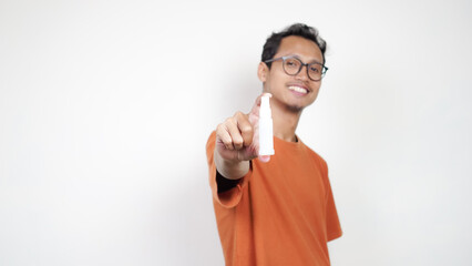 A man in an orange shirt is holding a bottle of medicine and pointing to it
